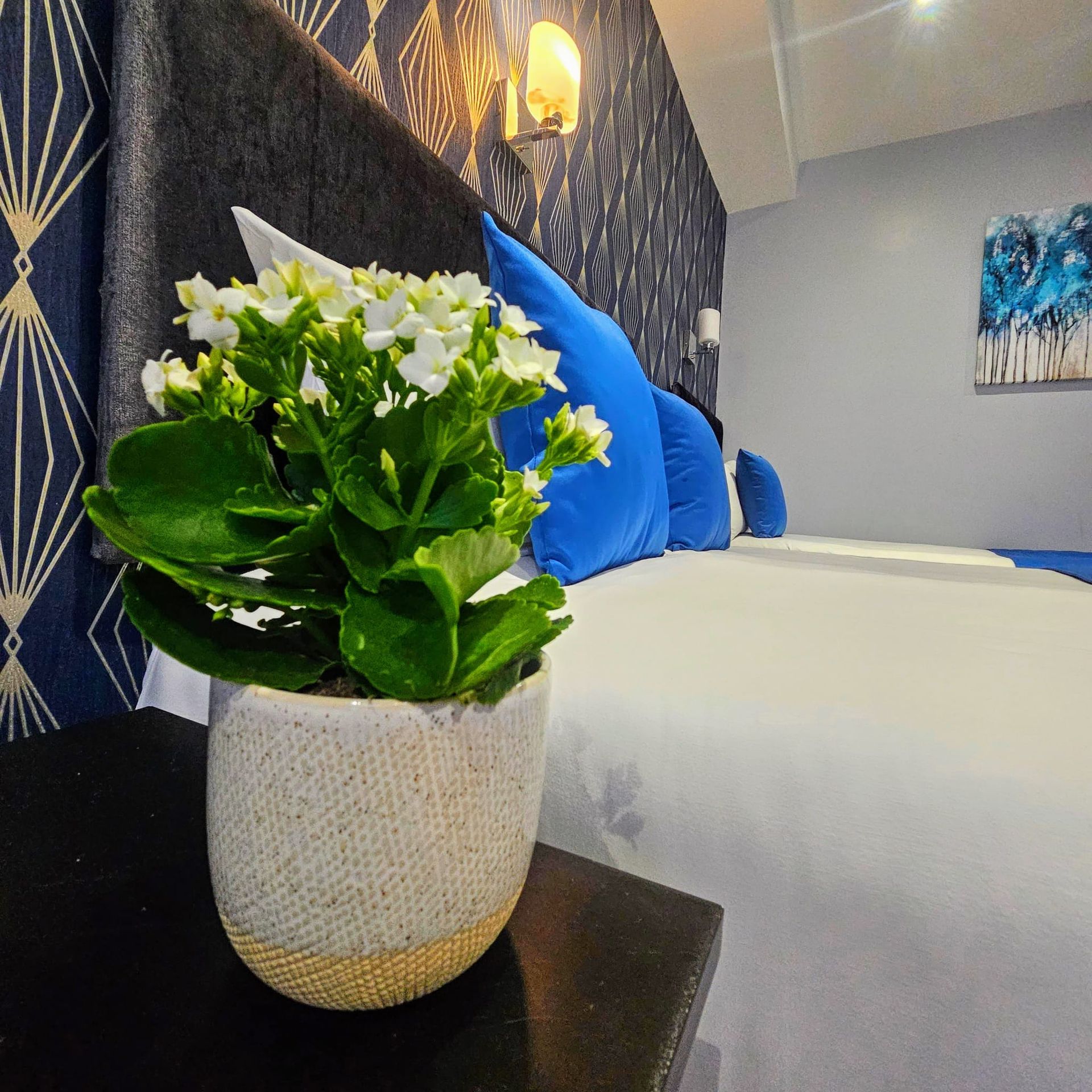 A potted plant is sitting on a nightstand next to a bed.