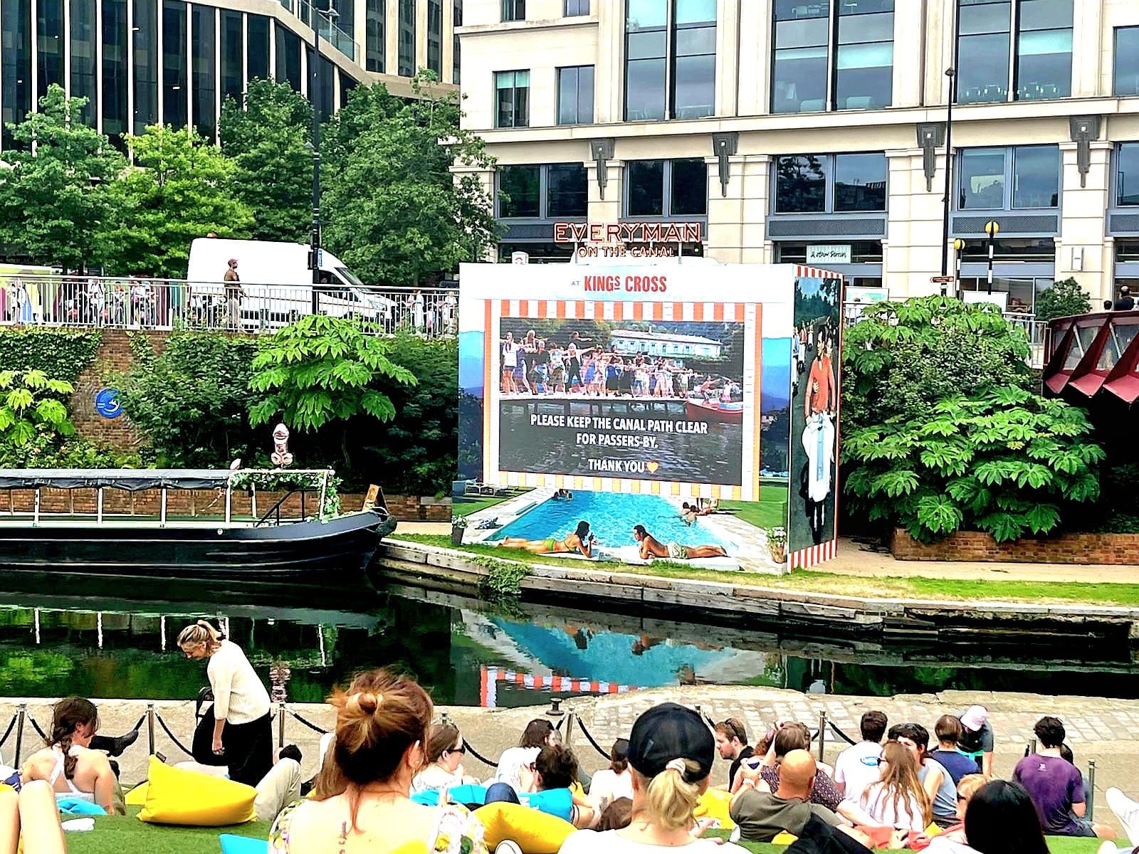 A group of people are sitting in front of a large screen.
