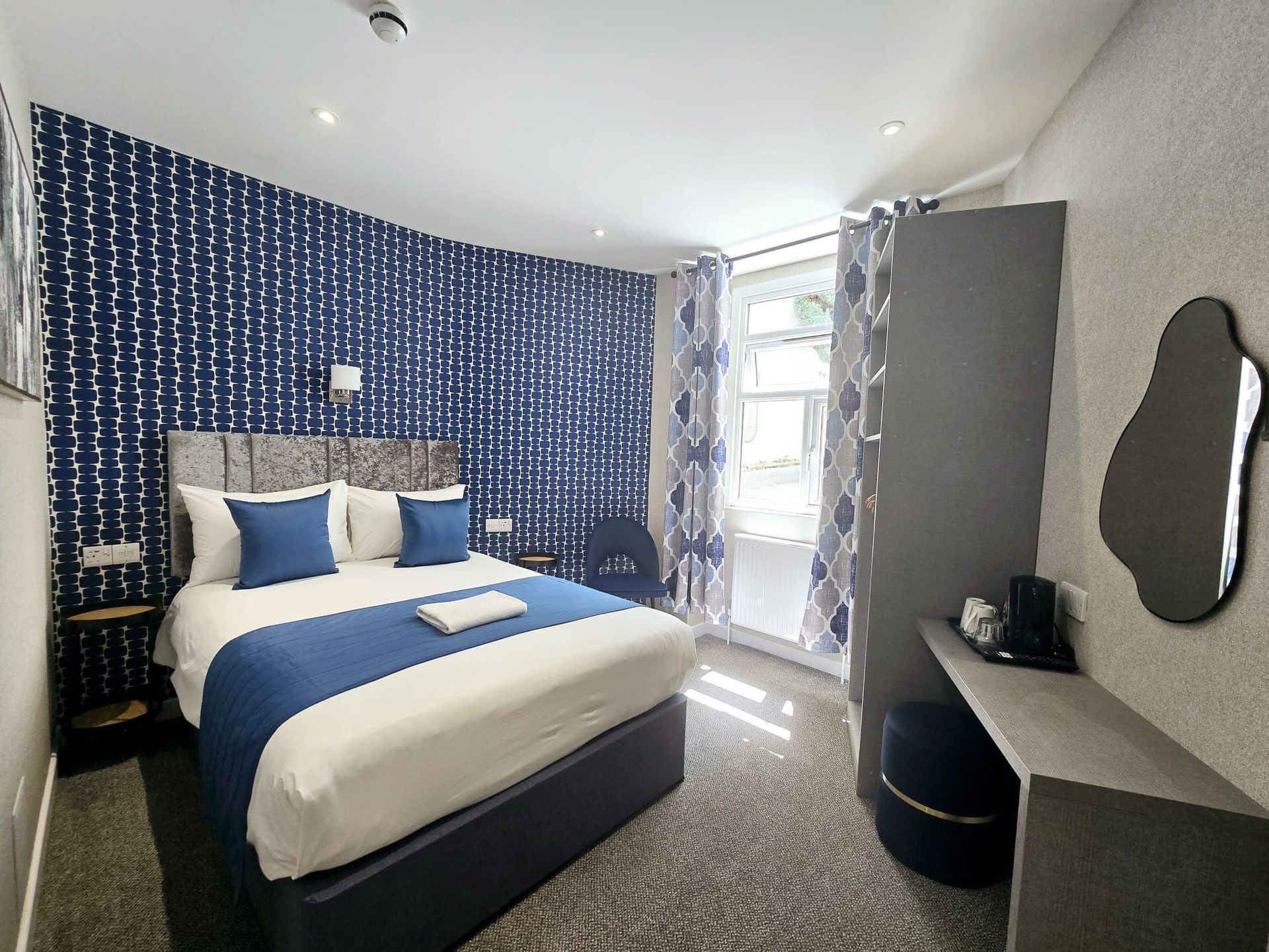 A potted plant is sitting on a nightstand next to a bed.