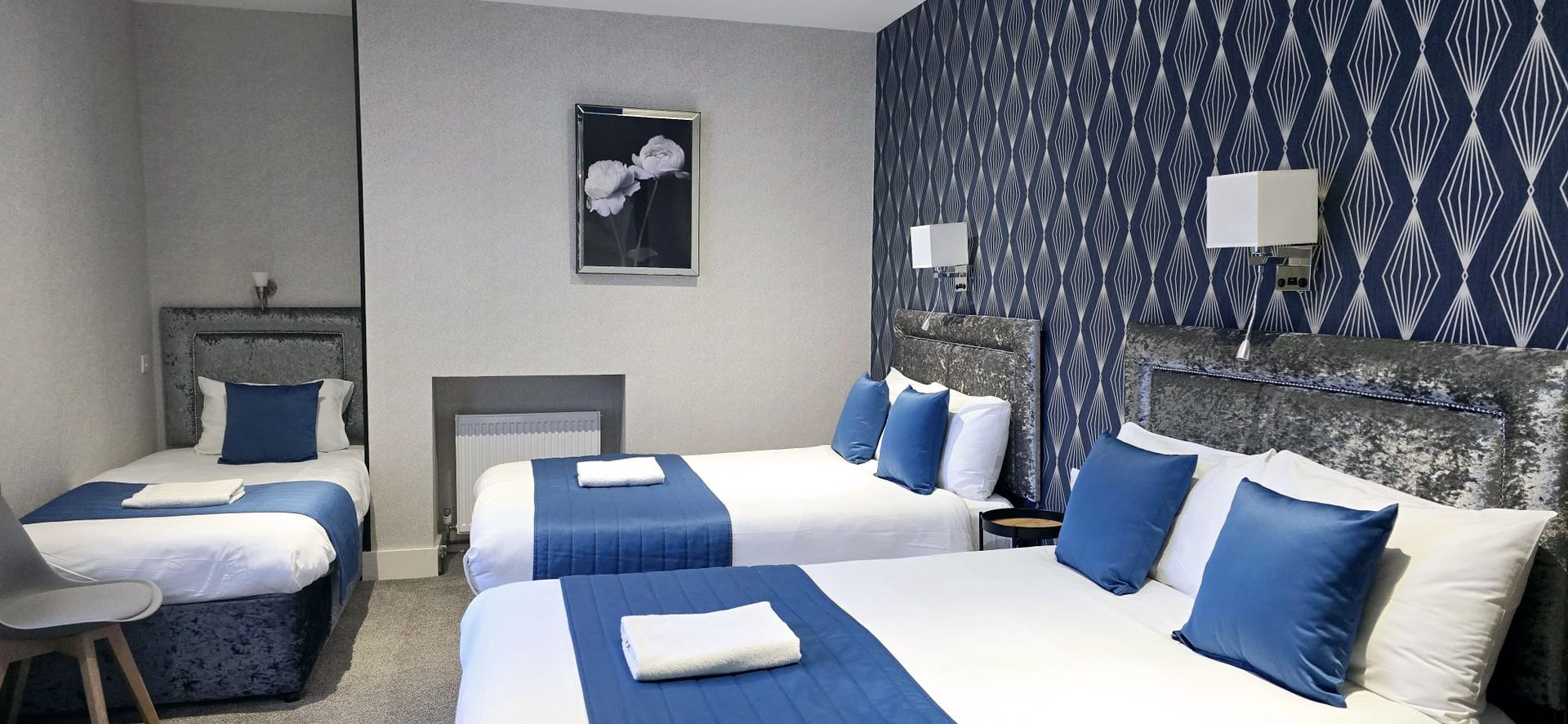 A hotel room with three beds and a picture on the wall.