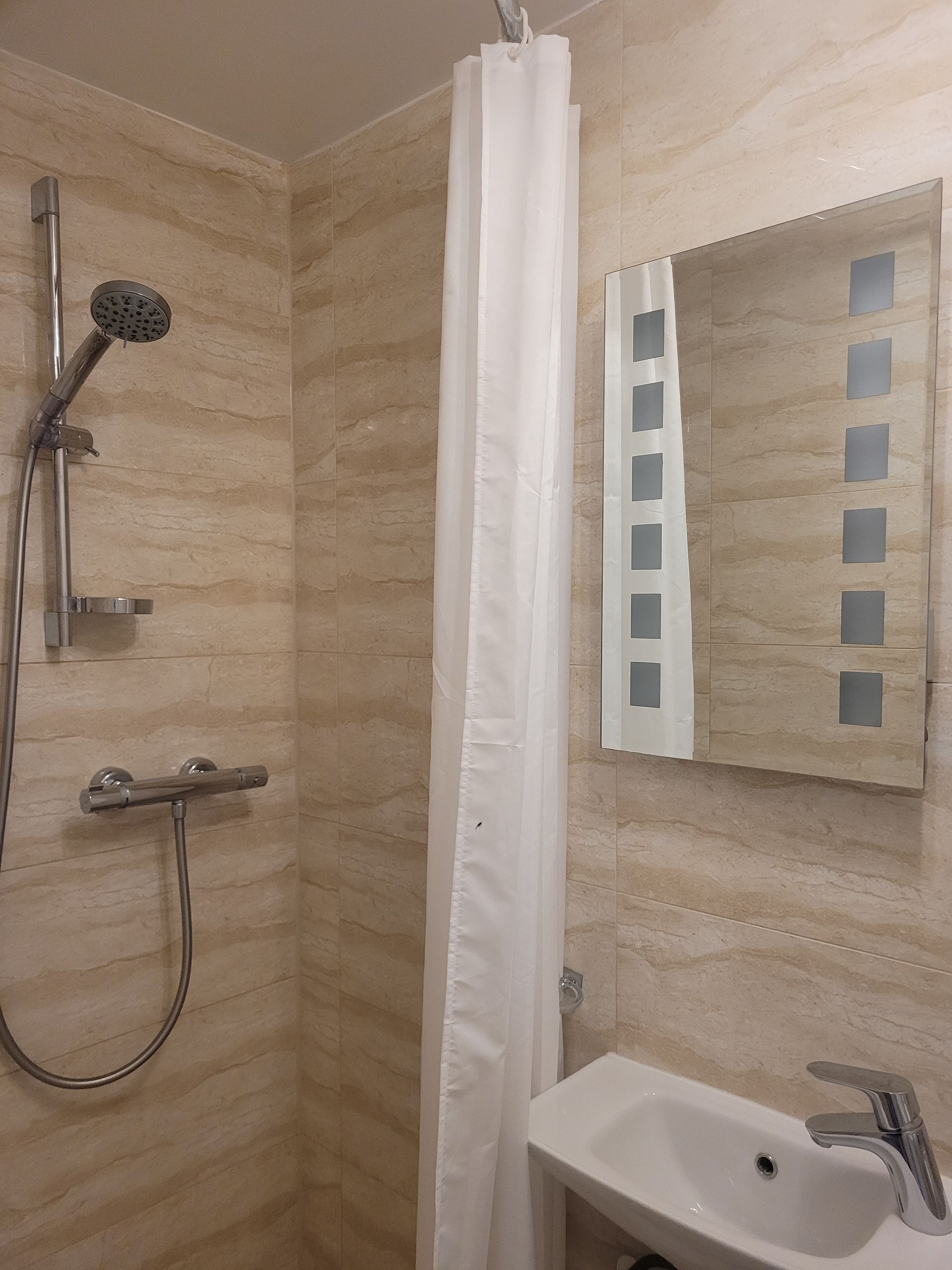 A bathroom with a shower , sink and mirror