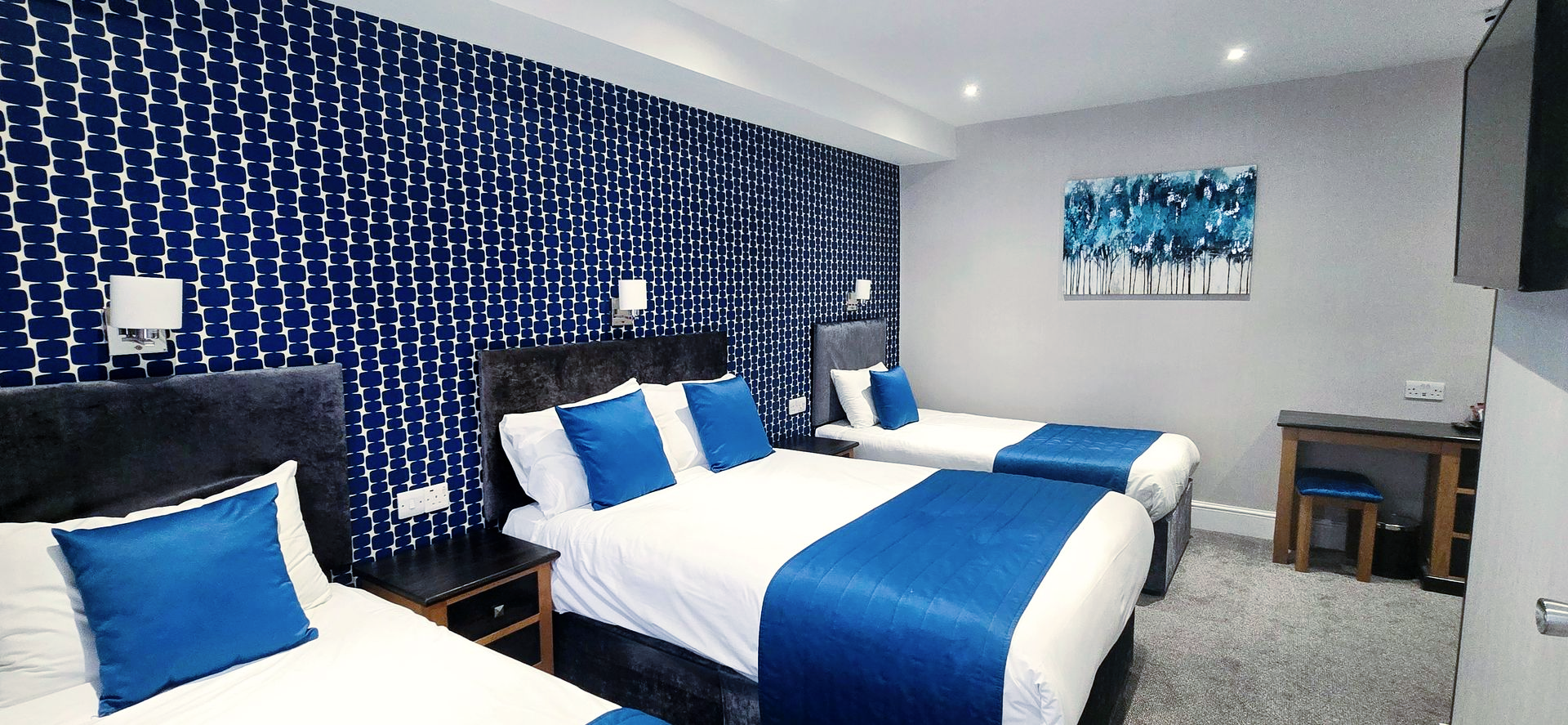 Hotel room with three beds, blue and white decor.