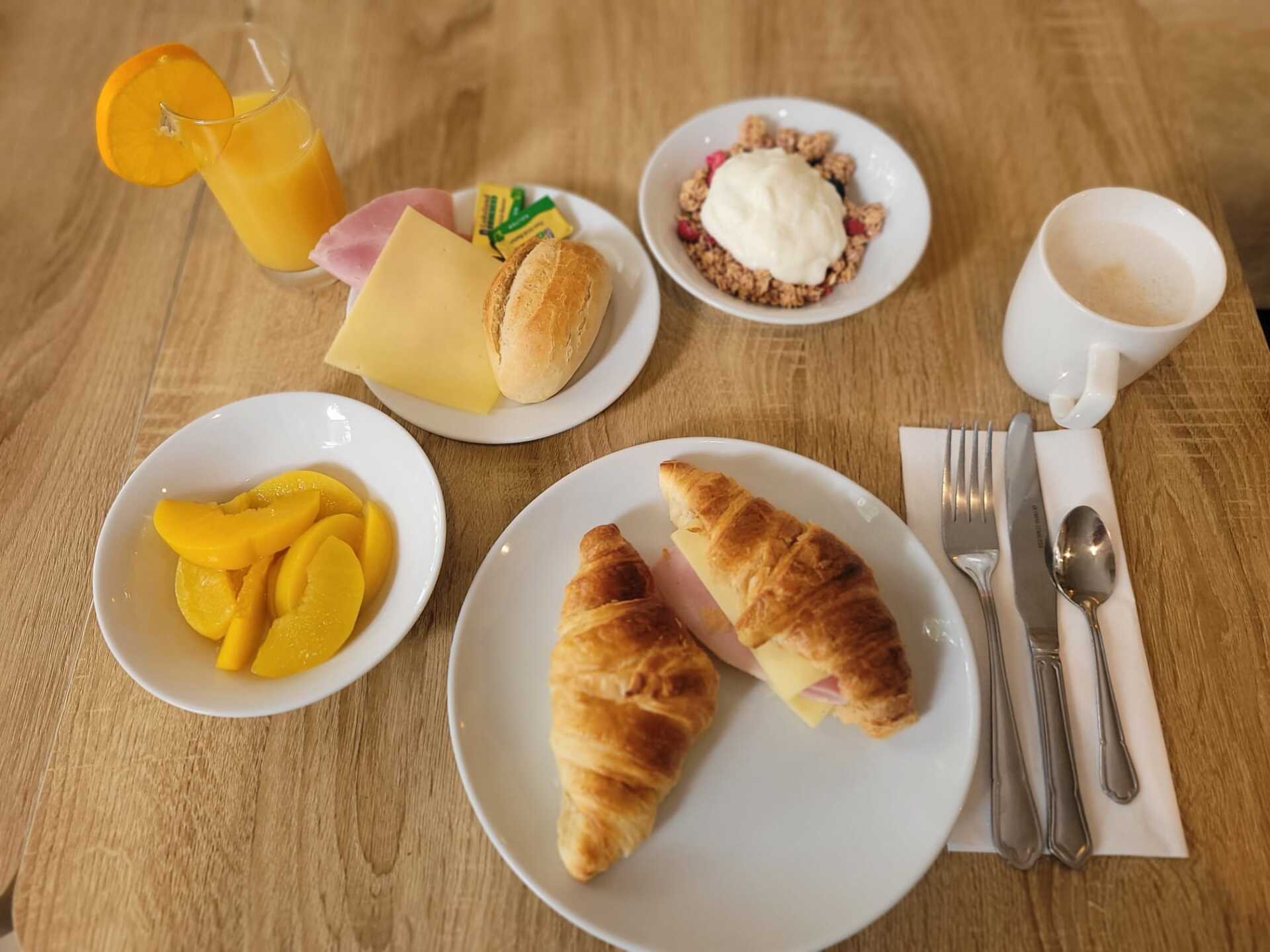 A table topped with plates of food and a glass of orange juice.