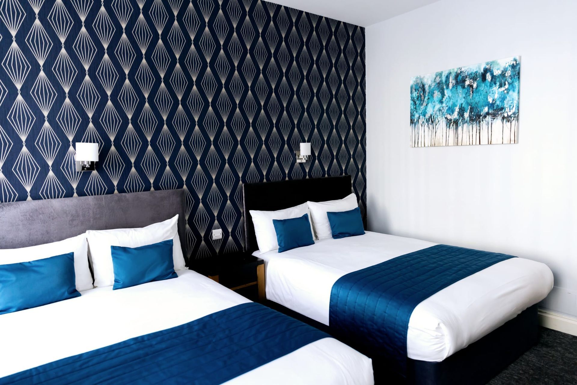 A hotel room with two beds and a painting on the wall