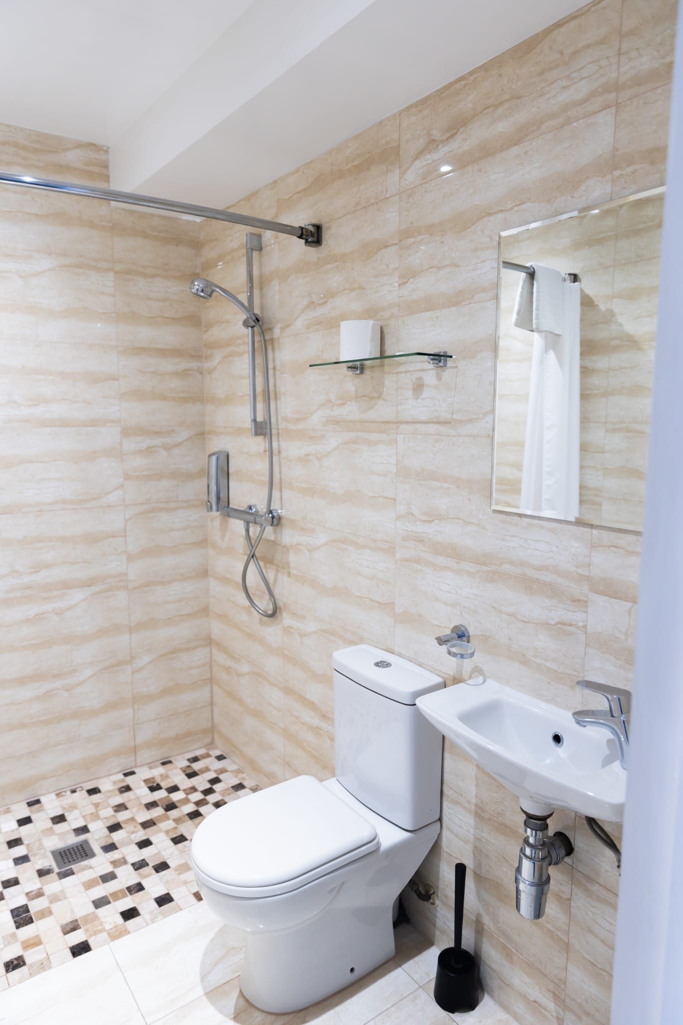 A bathroom with a toilet , sink and shower.