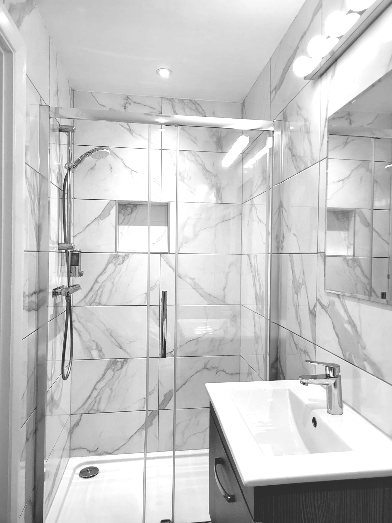 A bathroom with a sink , shower , and mirror.