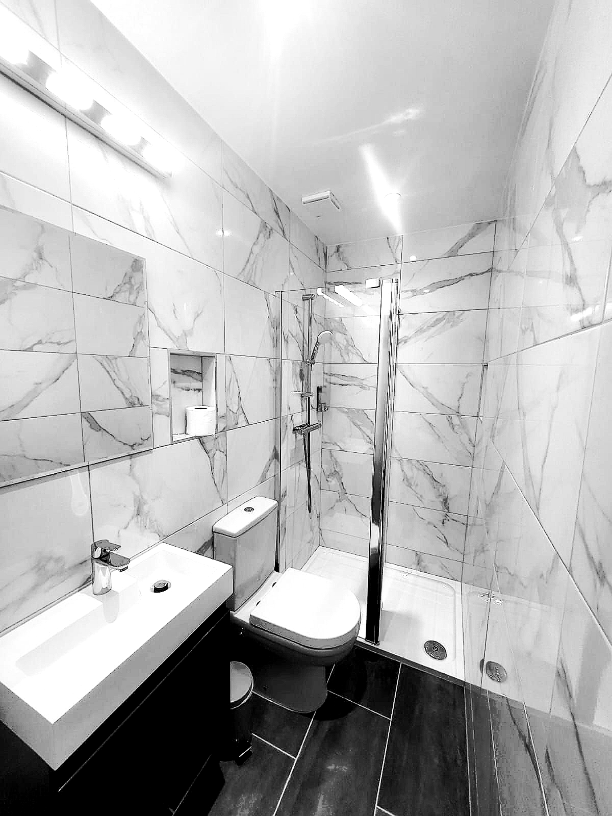 A bathroom with a sink , toilet , shower and mirror.