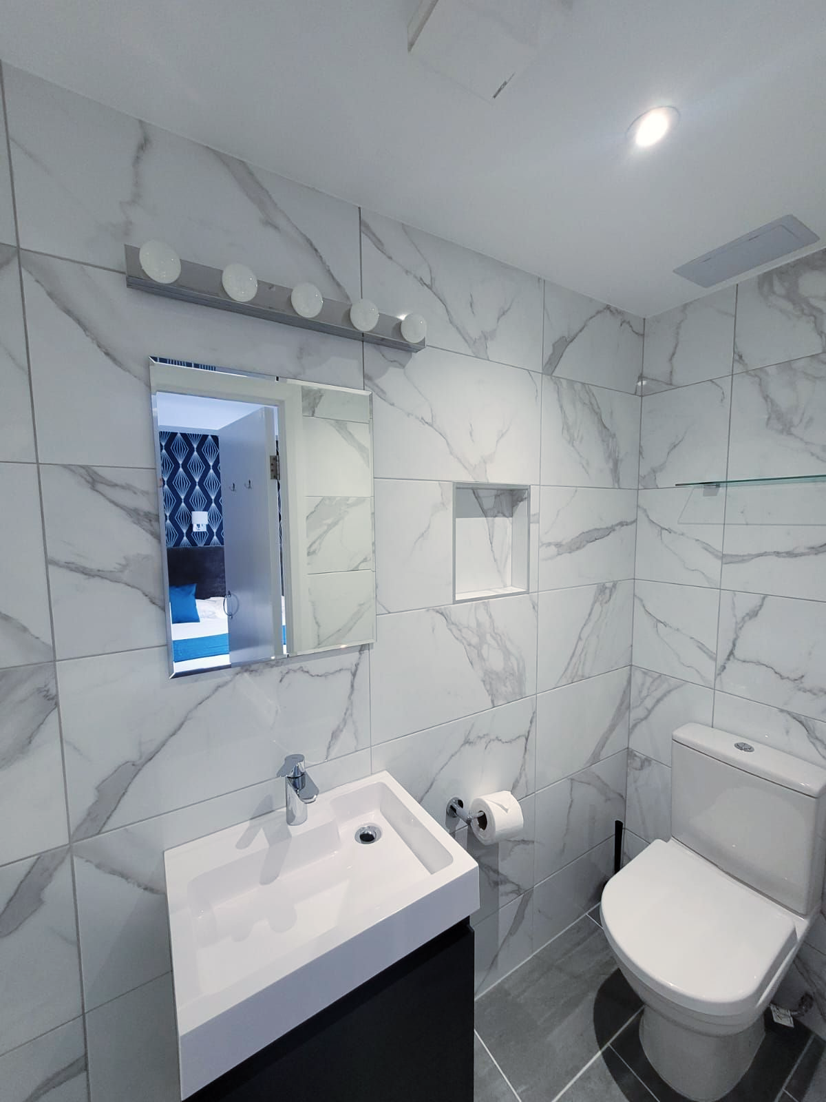 A bathroom with marble tiles and a sink and toilet