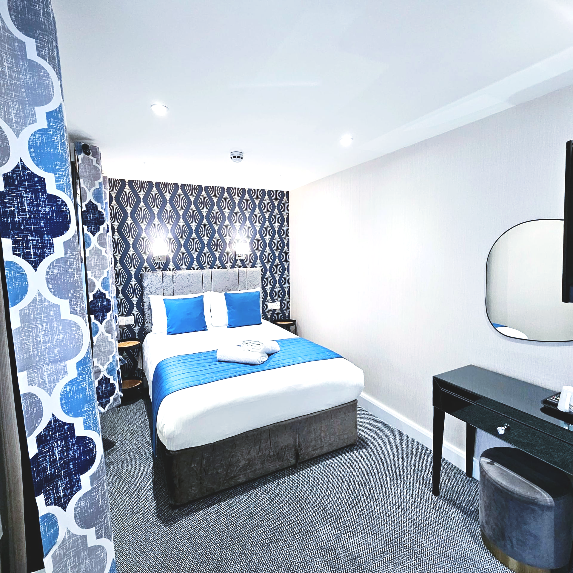 A hotel room with a large bed and a mirror