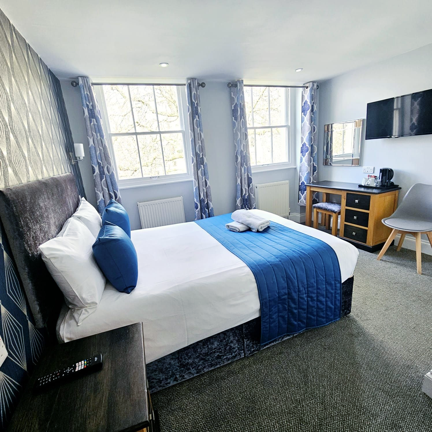 A hotel room with a bed , desk , chair and window.