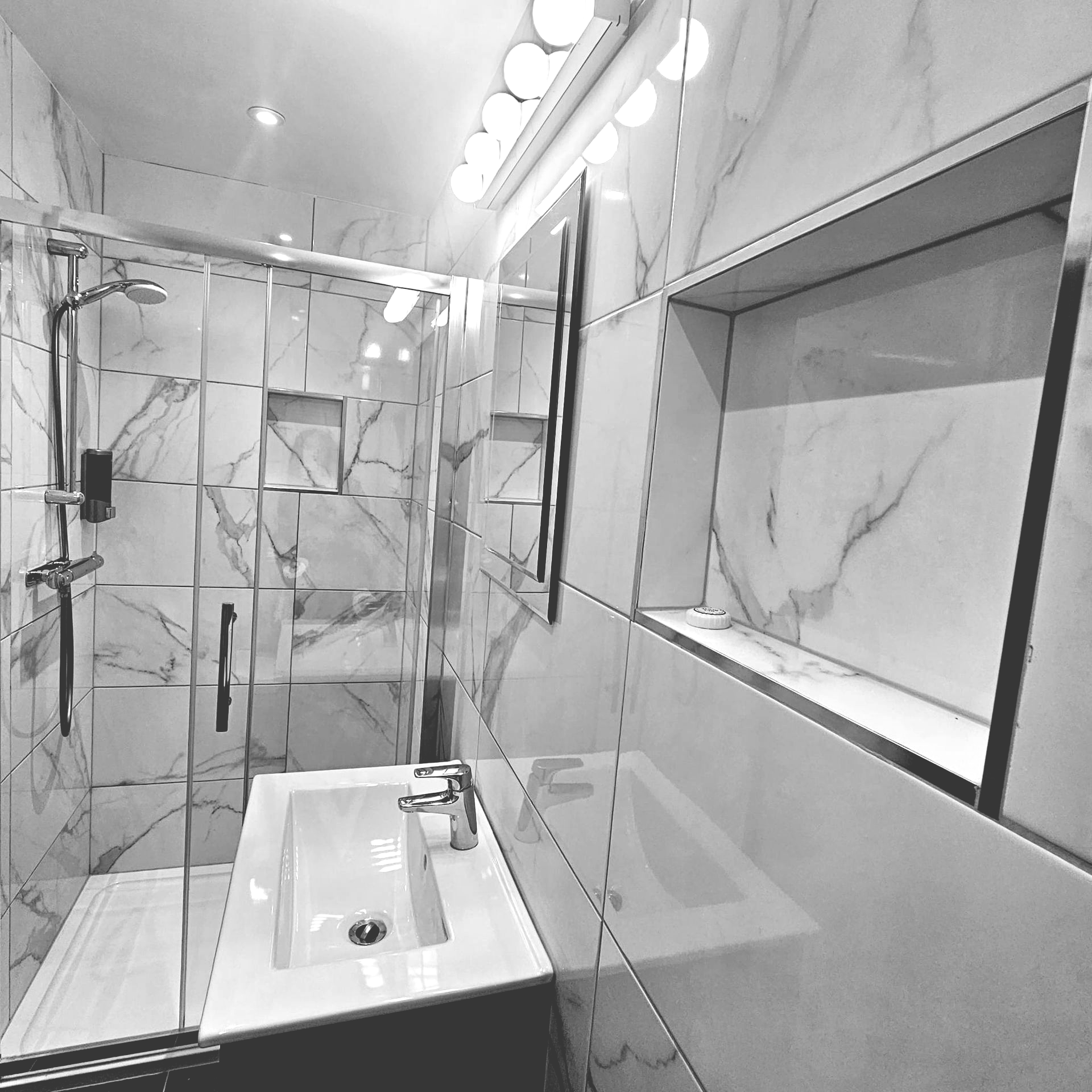 A bathroom with marble tiles and a sink and shower