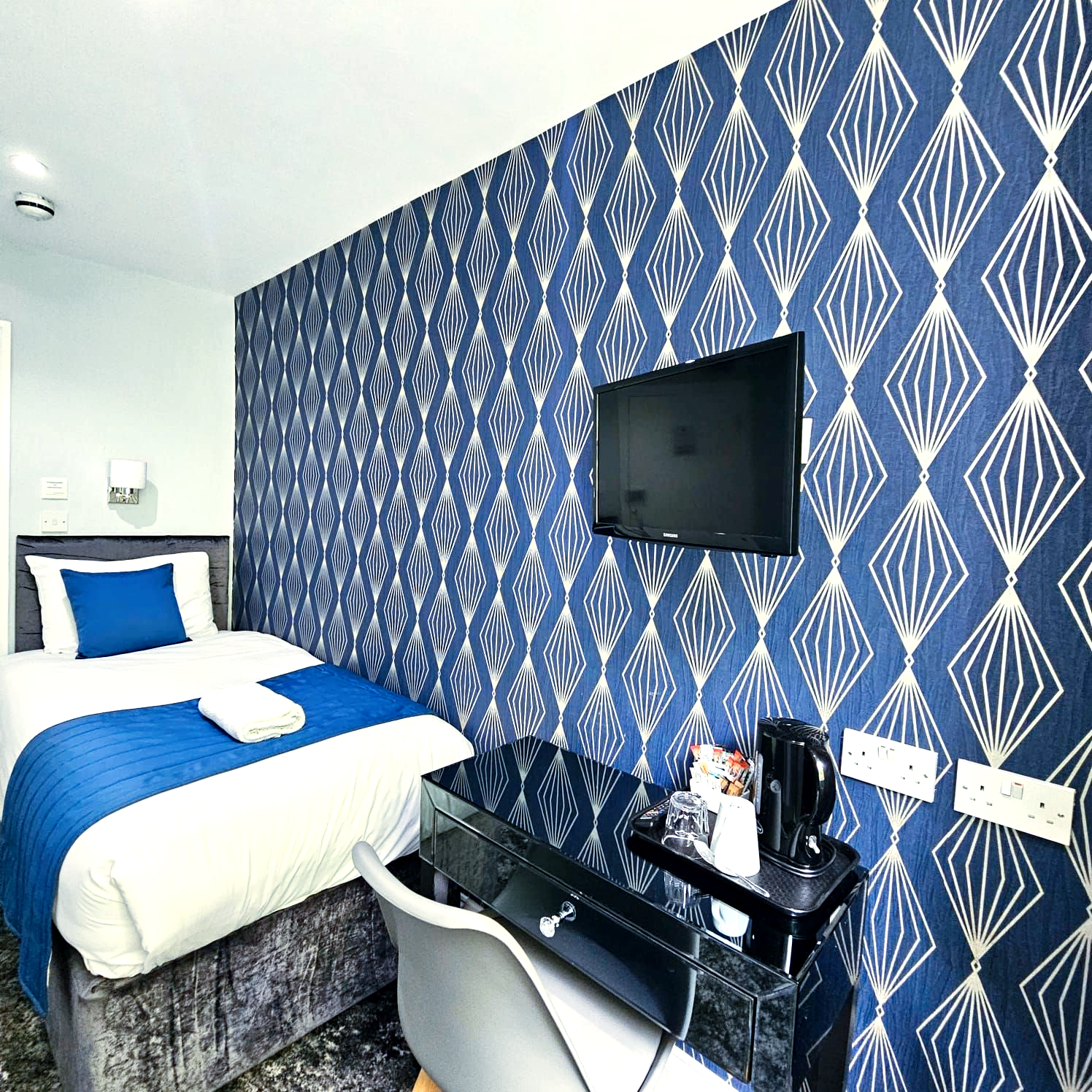 A hotel room with a single bed and a flat screen tv