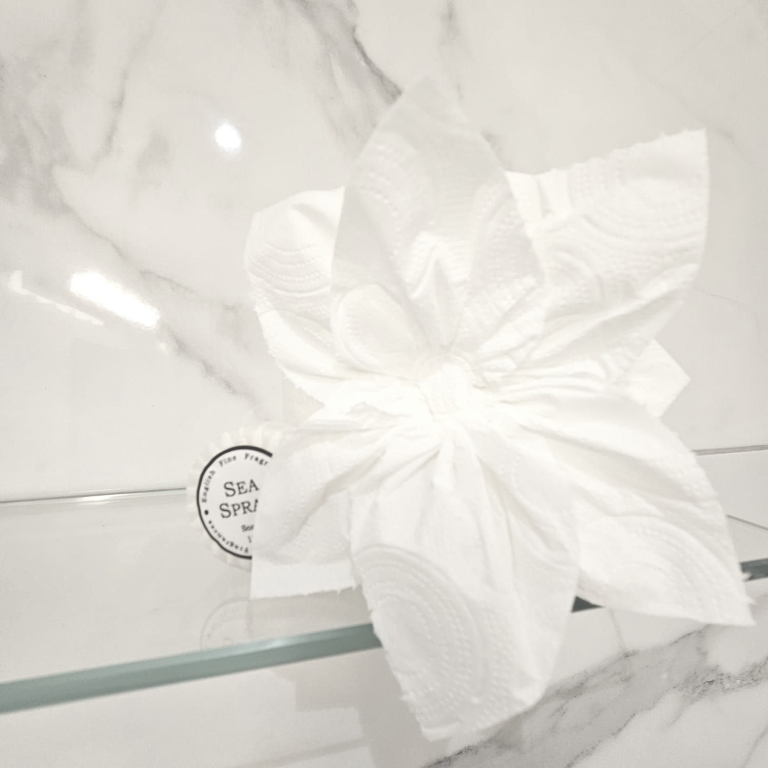 A white flower is on a glass shelf next to a sea spa logo