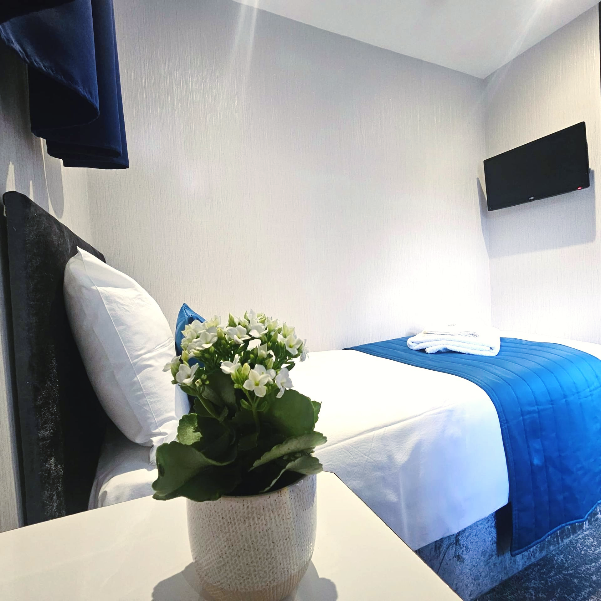 A bedroom with a bed and a vase of flowers on a table.