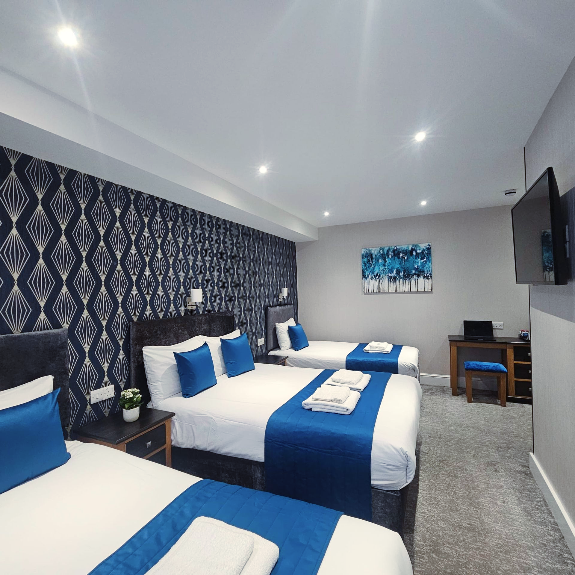 A hotel room with three beds and a flat screen tv