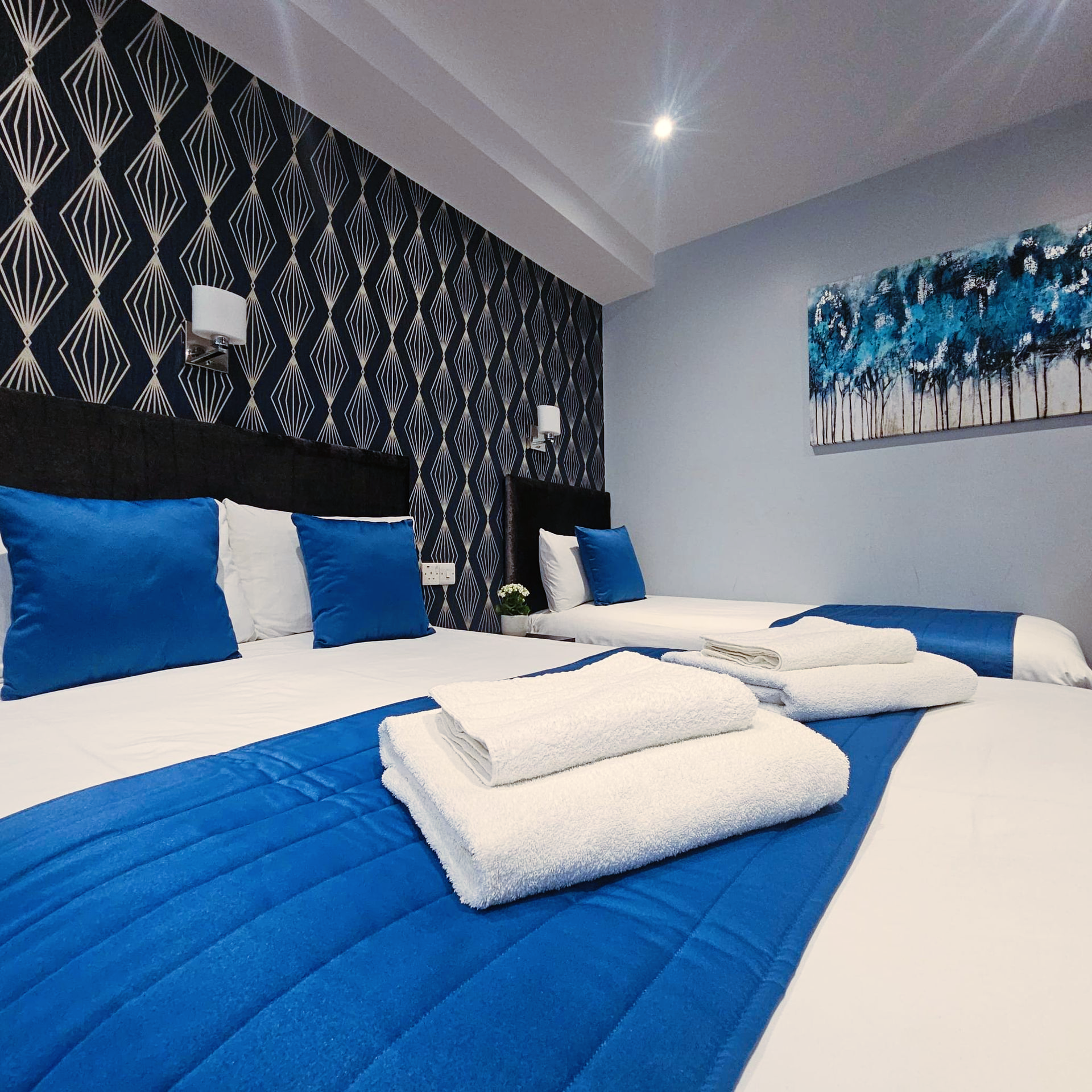 A hotel room with two beds and a painting on the wall
