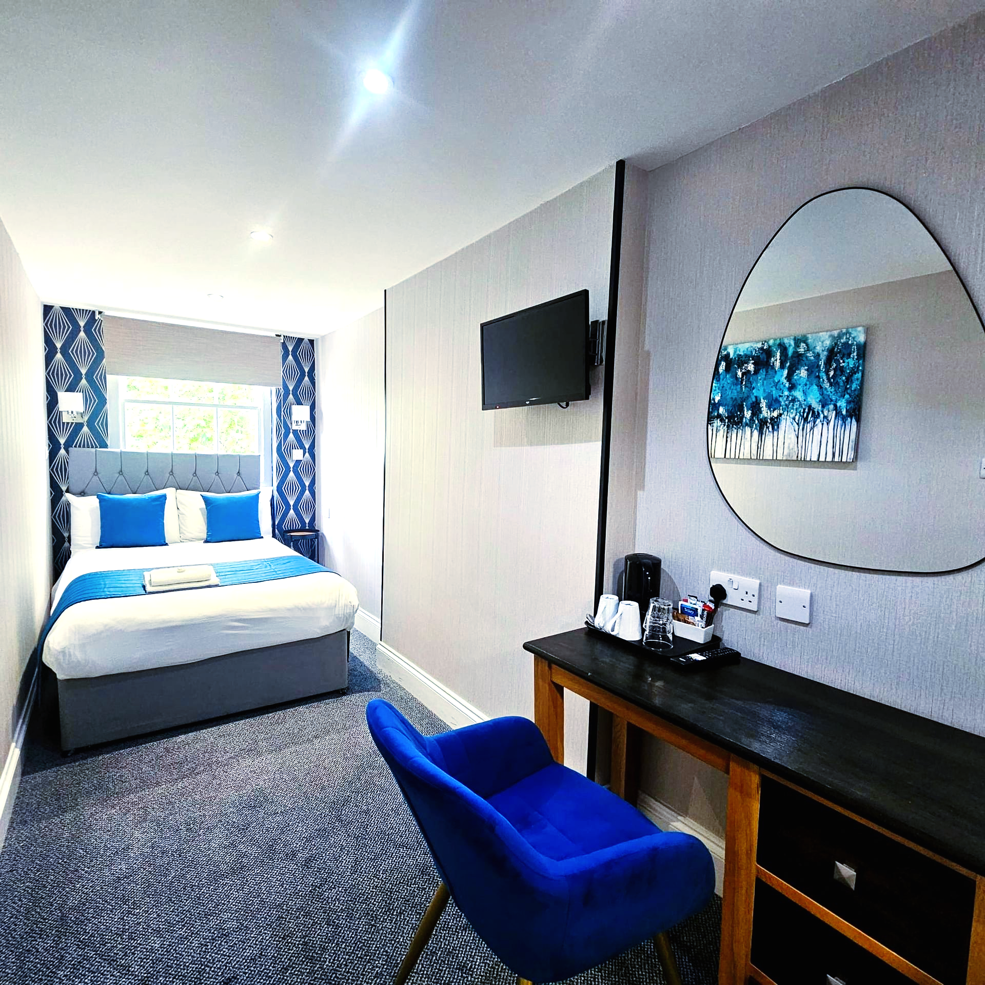 A hotel room with a bed , desk , chair and television.