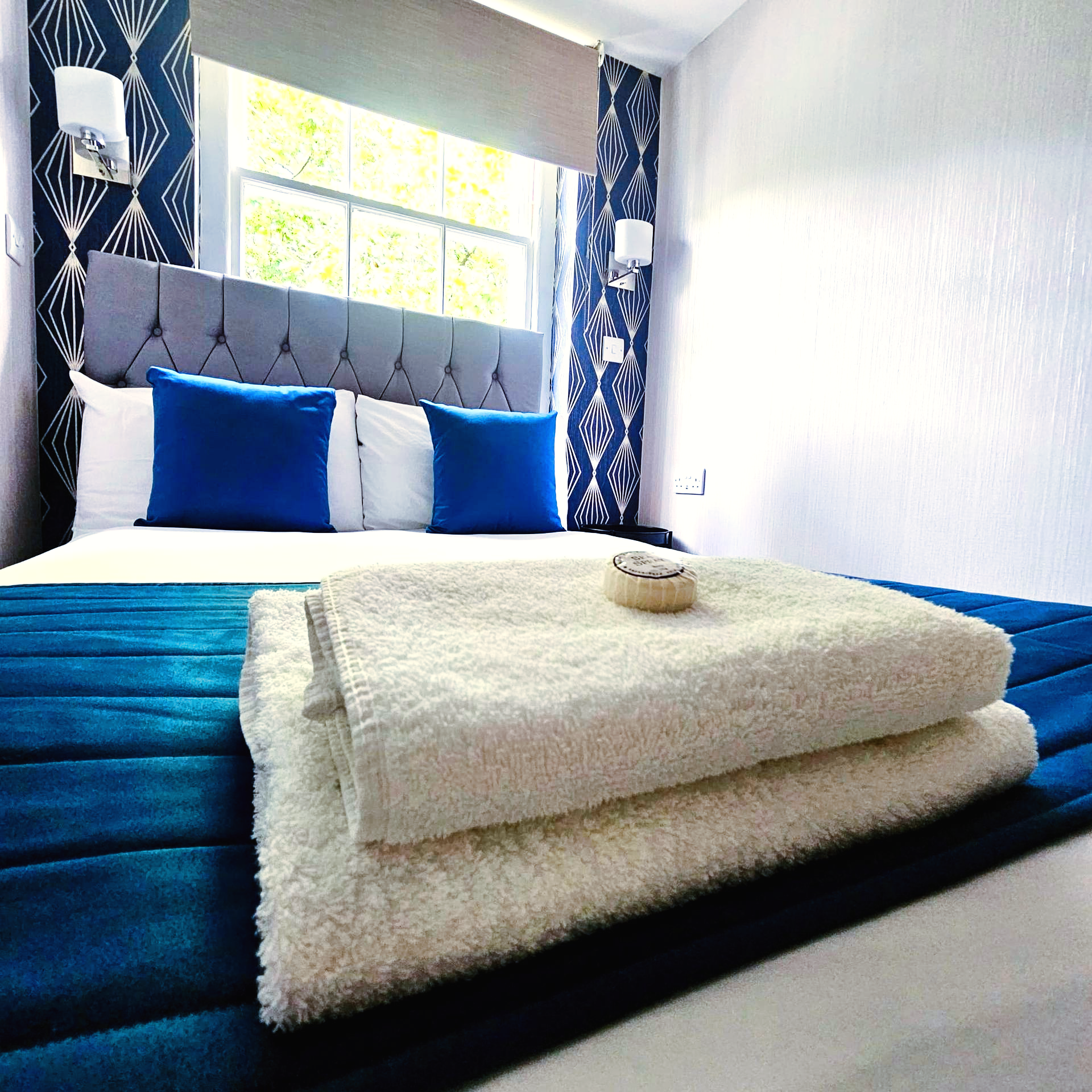 A bed with blue sheets and white towels on it