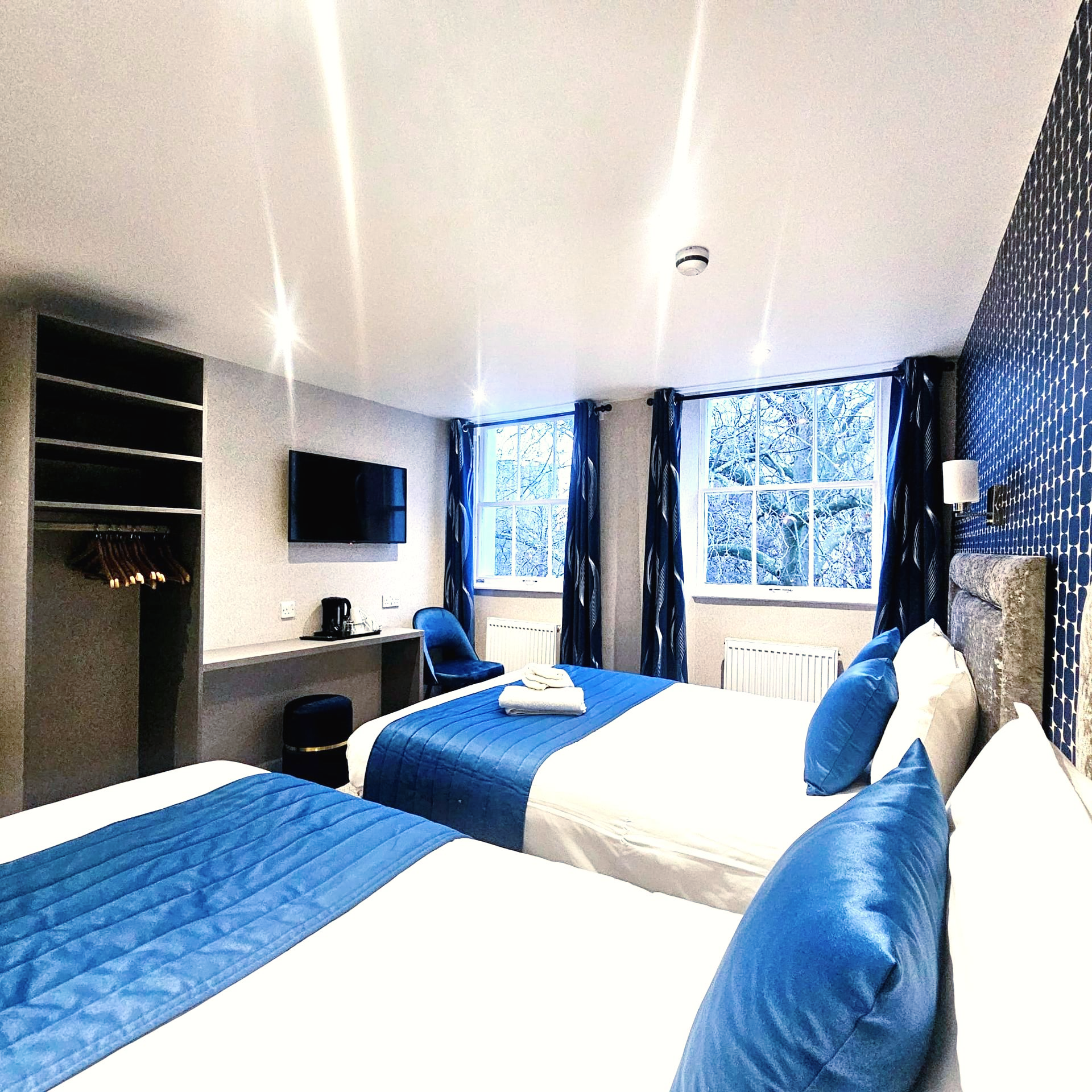 A hotel room with two beds and blue curtains