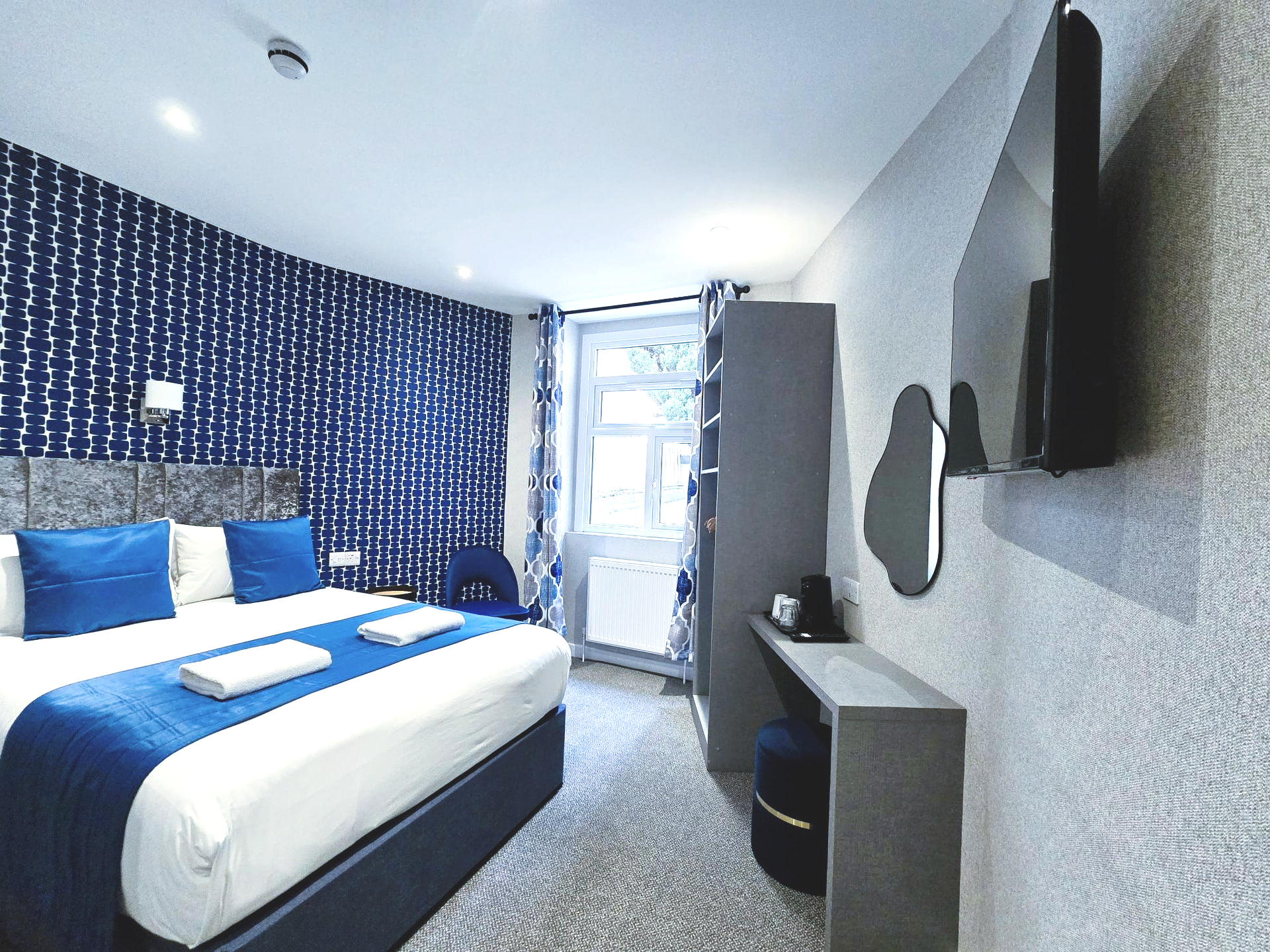 A hotel room with a king size bed and a flat screen tv.