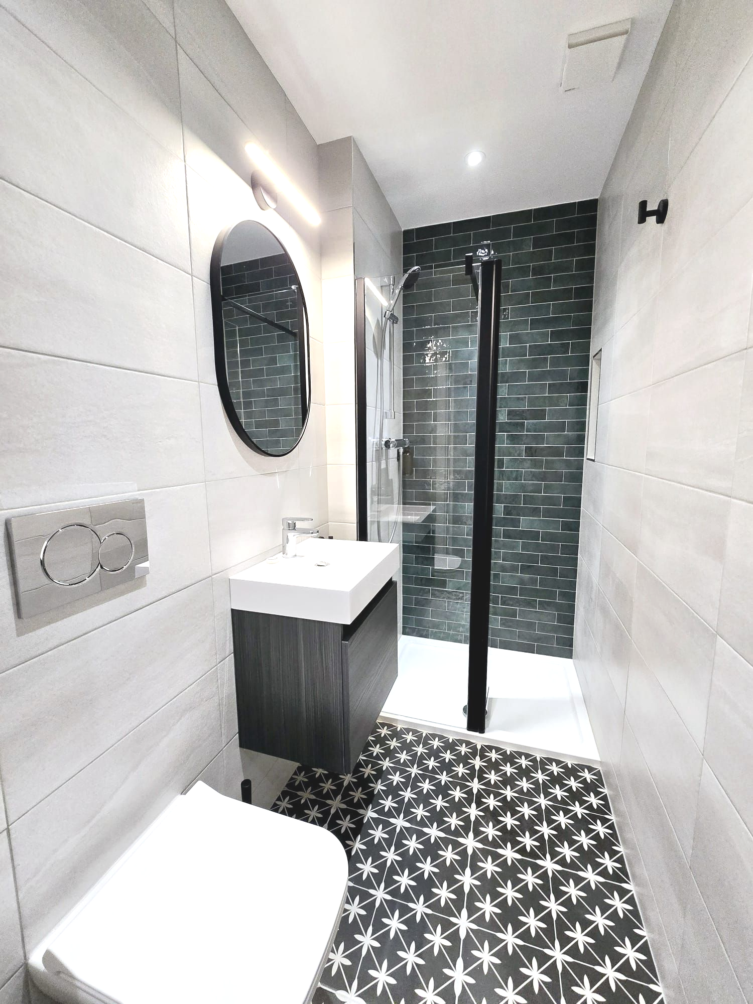 A bathroom with a toilet , sink , mirror and walk in shower.