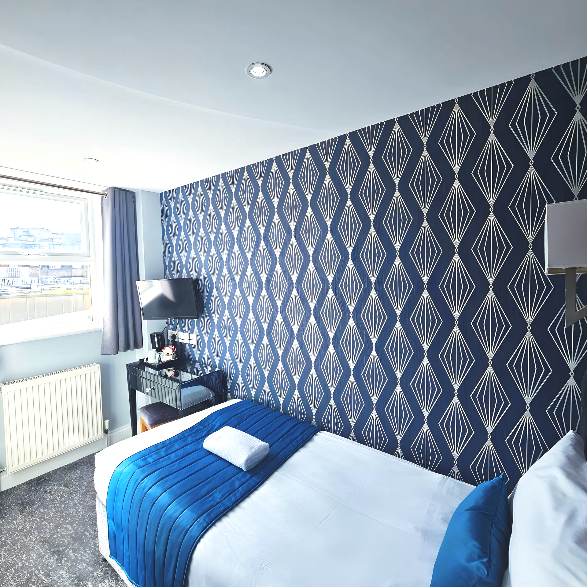 A hotel room with blue and white wallpaper and a bed