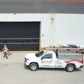 Warehouse exterior with open loading bay, worker on forklift, and white pickup truck in front