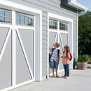 Two children standing outside a gray barn-style building with white-framed windows and doors
