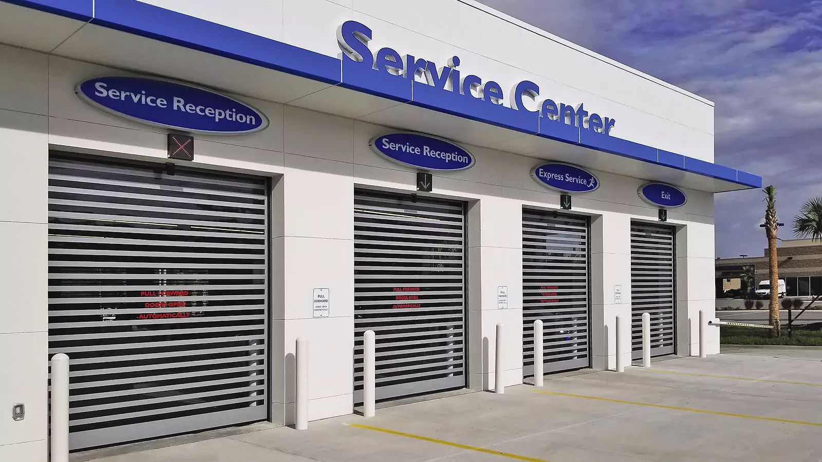Service Center storefront with white roll-up doors and blue signage above each bay