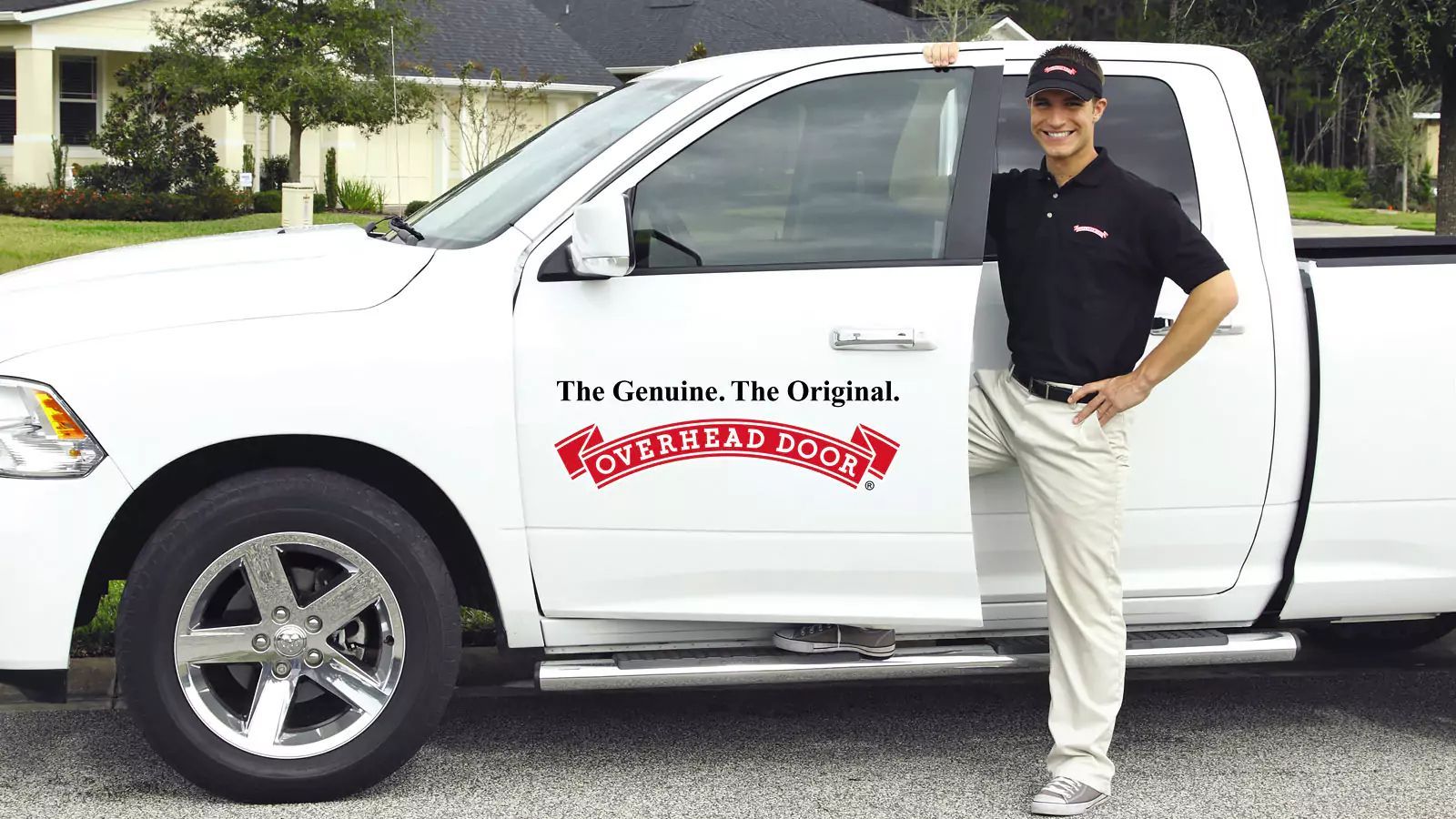 Man standing beside a white pickup truck with company branding on the door.