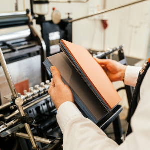 Worker hands inspecting a black-and-orange chain in an industrial workshop