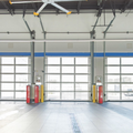 Empty fire station garage with three roll-up bay doors and yellow safety bollards