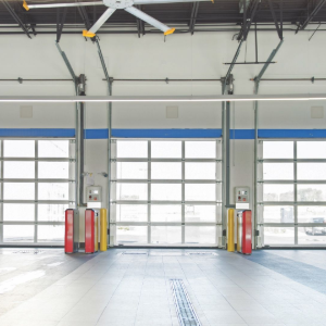 Empty fire station garage with three roll-up bay doors and yellow safety bollards