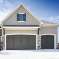 Modern suburban house with beige siding, three-car garage, and flower beds by the front walkway