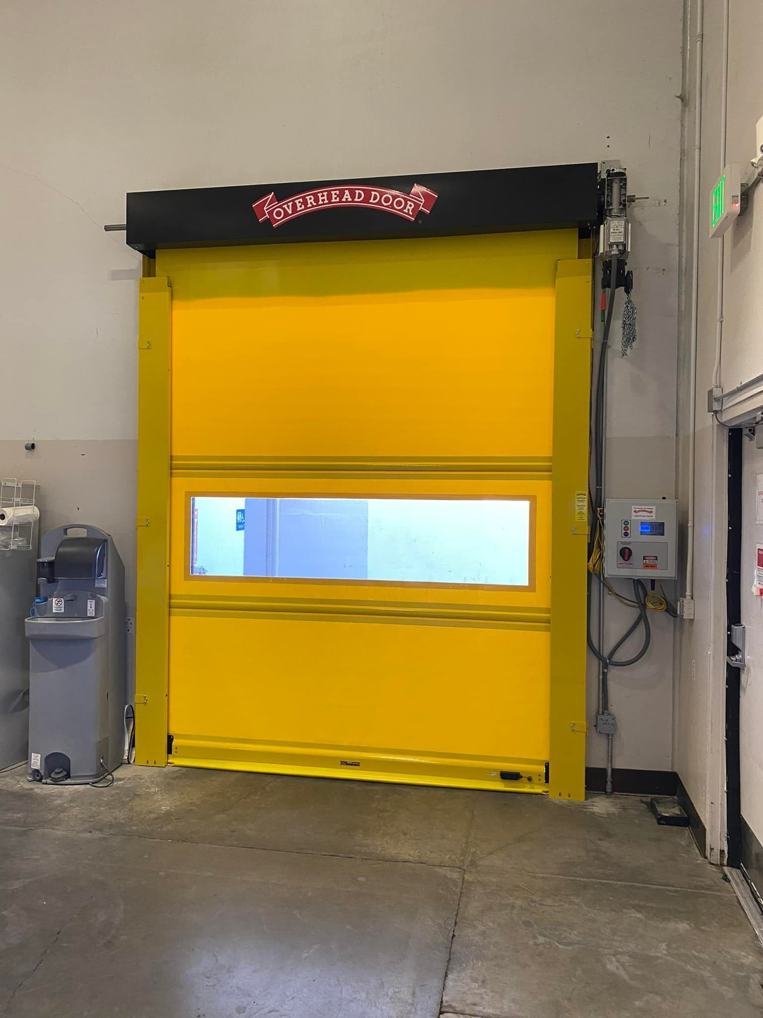 Yellow industrial garage door with a small window in a warehouse setting