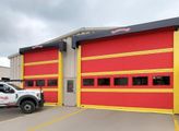 Red fire station with two large garage doors and a white utility truck parked outside
