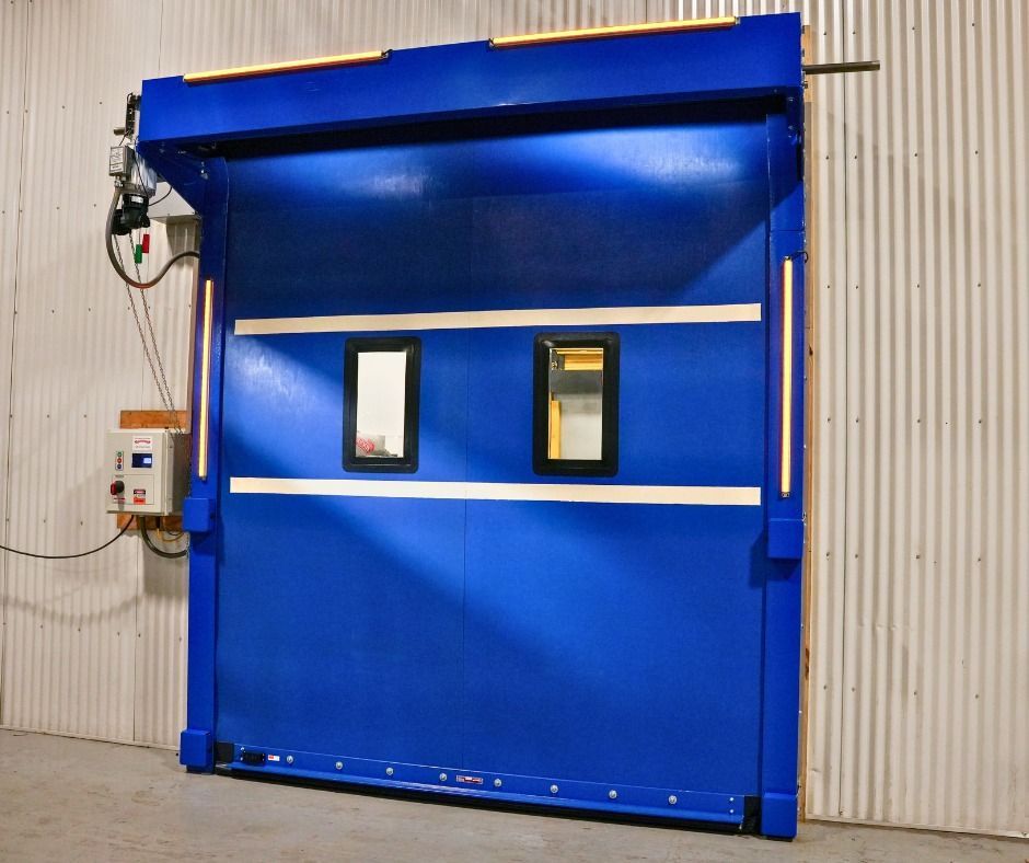 Blue industrial roll-up door with two small windows in a warehouse setting