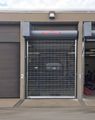 Closed storefront with metal roll-up gate, black awning, and unit number 2 on the left side of a garage-like entrance