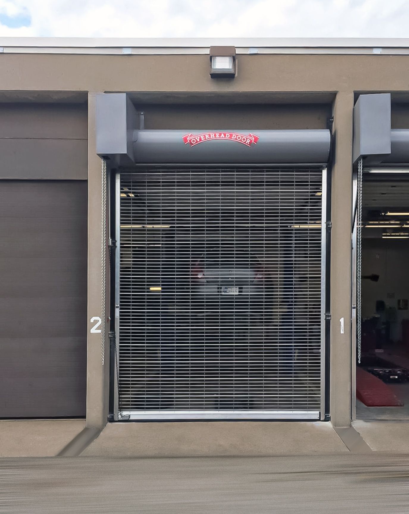 Closed storefront with metal roll-up gate, black awning, and unit number 2 on the left side of a garage-like entrance