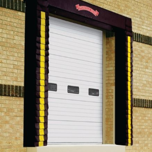 White loading dock door set in a brick wall, framed by black and yellow protective bumpers.