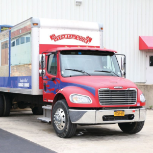 Red delivery truck parked outside a warehouse loading dock