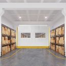 Bright warehouse aisle with stacked boxes on shelves and a white wall at the end