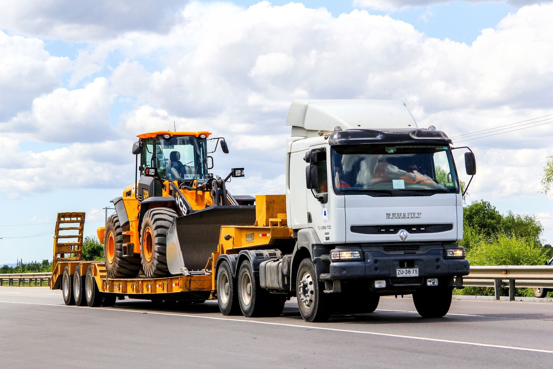 A truck is carrying a bulldozer on a trailer on a highway.