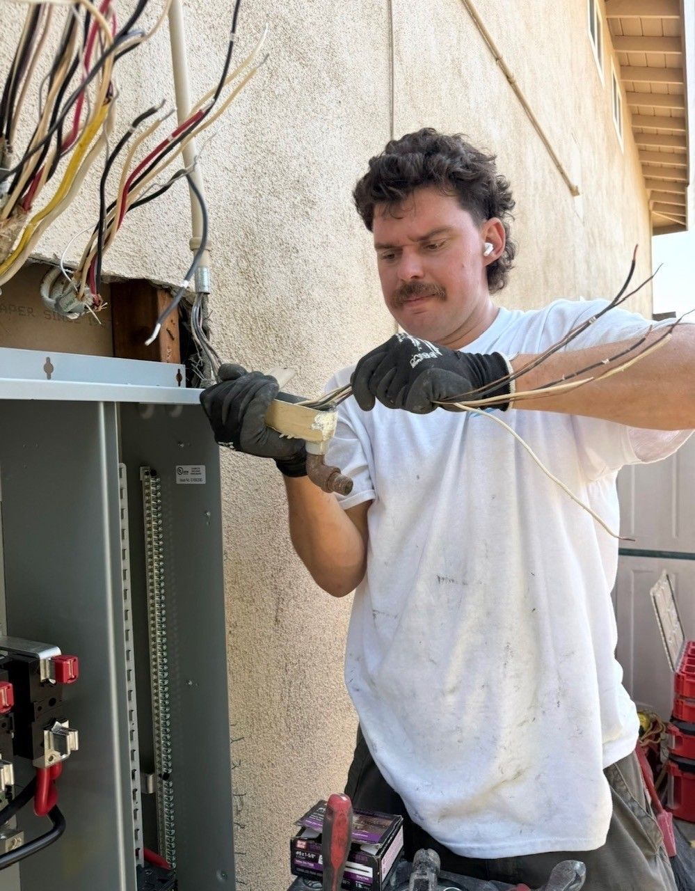 Man in blue shirt working beside a water heater and laundry machine in a utility room