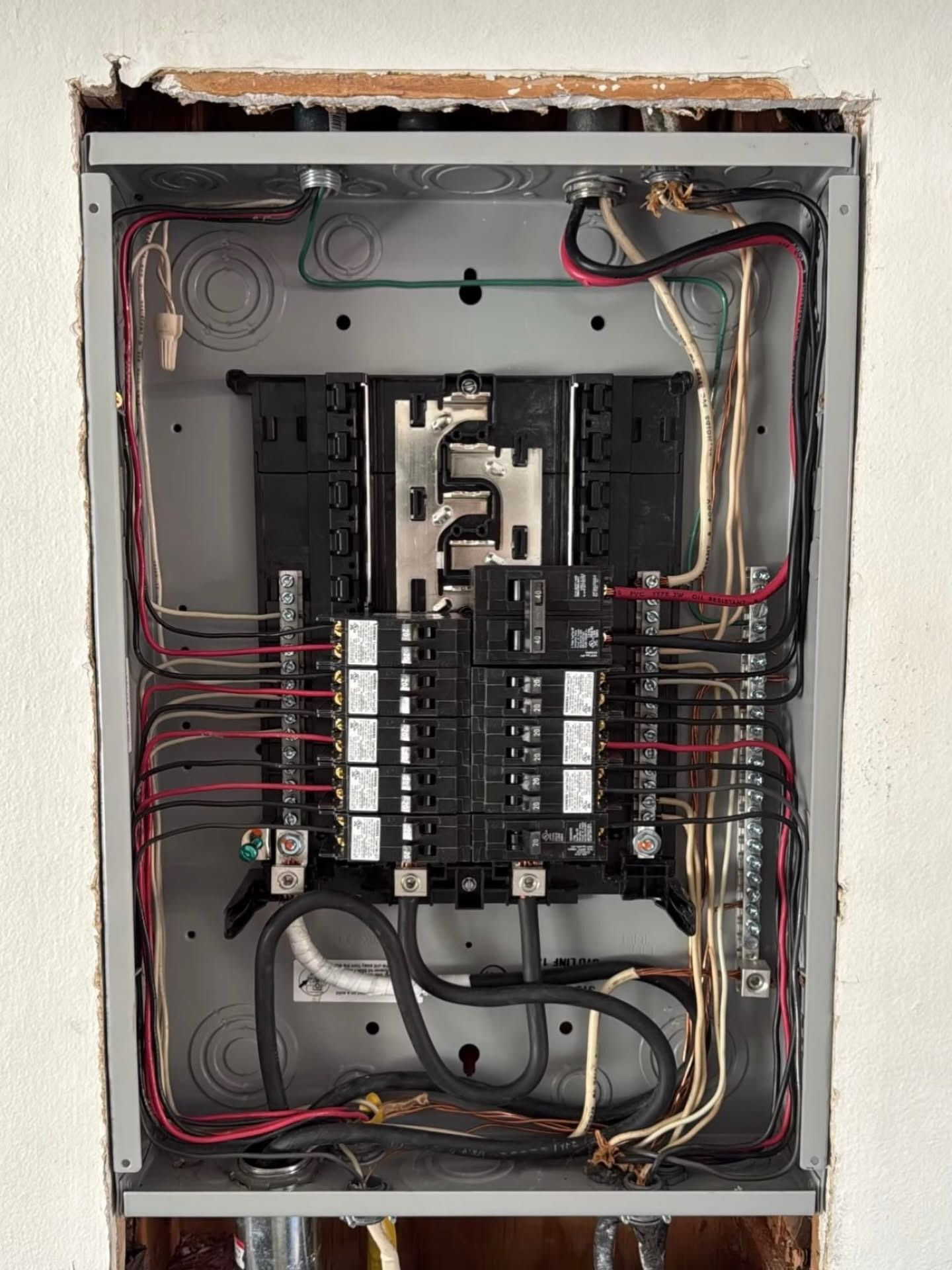 Open electrical breaker panel with wiring and circuit breakers exposed