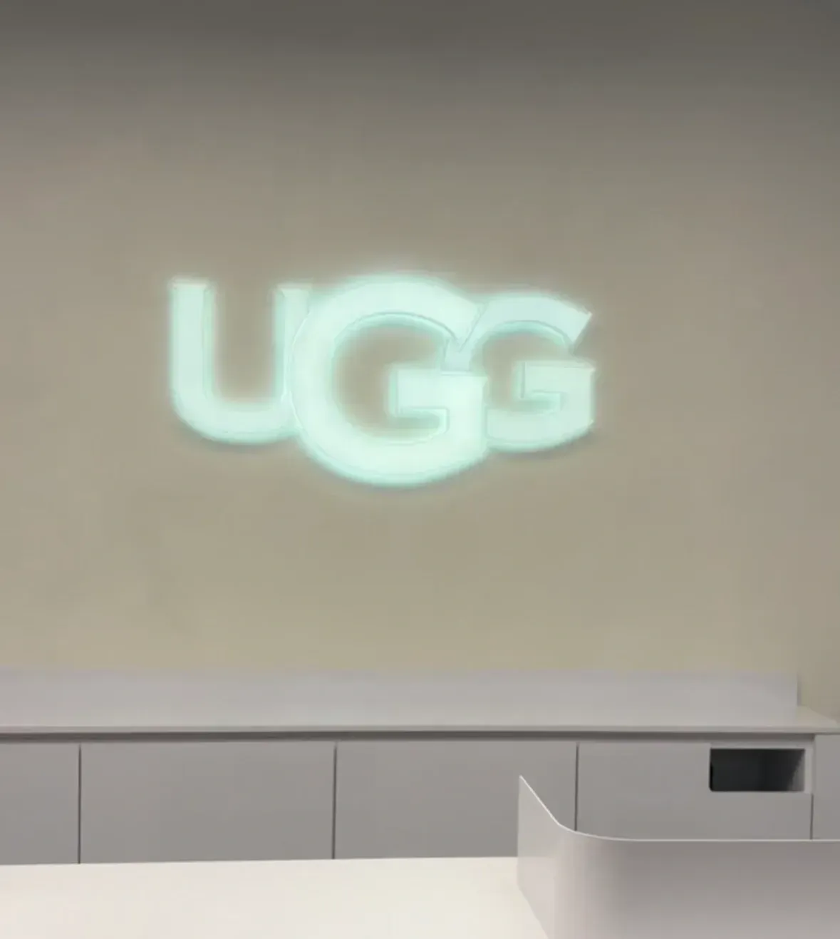 Projected UGG logo glowing on a light wall above white cabinets