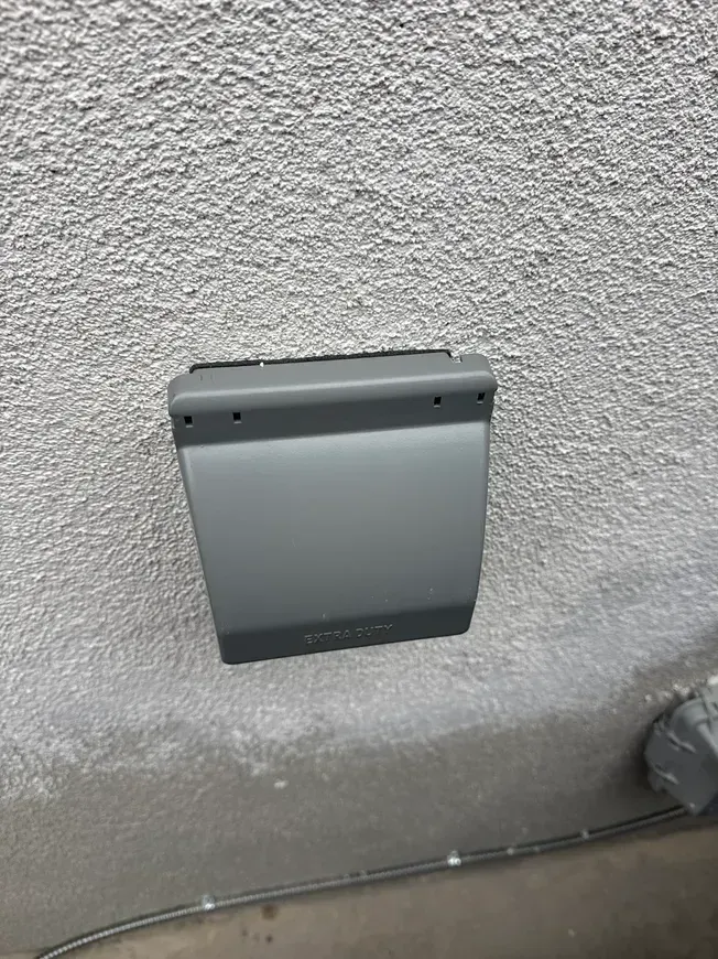 Gray wall-mounted electrical box on a textured wall, with conduit along the floor. Gray wall-mounted electrical box on a textured wall, with conduit along the floor.