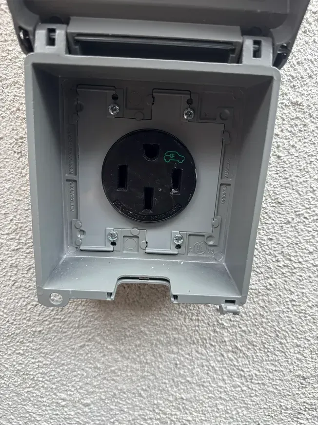 Open outdoor electrical outlet in a gray weatherproof wall box