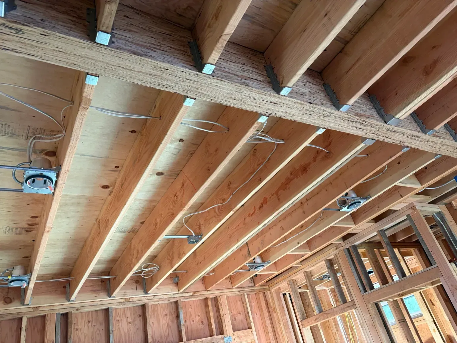 Exposed wooden ceiling joists and rafters in an unfinished room under construction