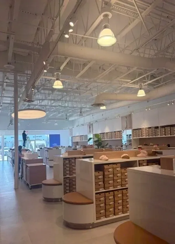 Spacious warehouse-style retail store with white shelves, rows of small boxes, and high industrial ceilings.
